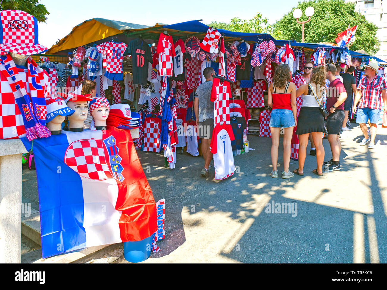 La gente la contrattazione con il fornitore in uno stand di souvenir, Quayside, Split, Croazia. Rosso e bianco vestiti a tema sostiene la Croazia di Coppa del Mondo di socce vincente Foto Stock