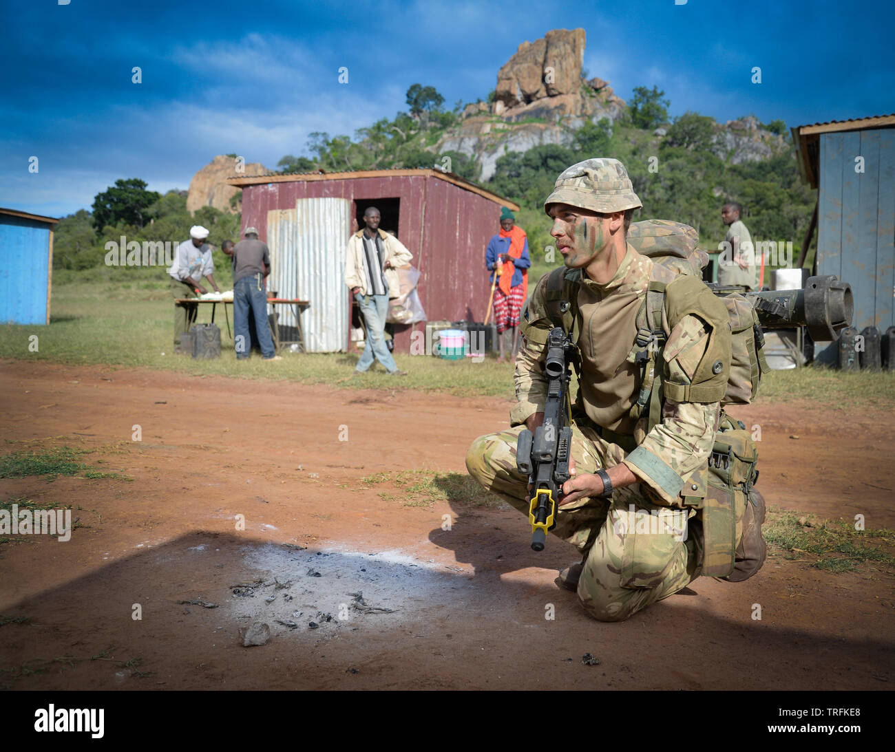 Un membro del Reggimento paracadutisti della formazione in Kenya con locali impiegati per agire come popolazione civile. Foto Stock