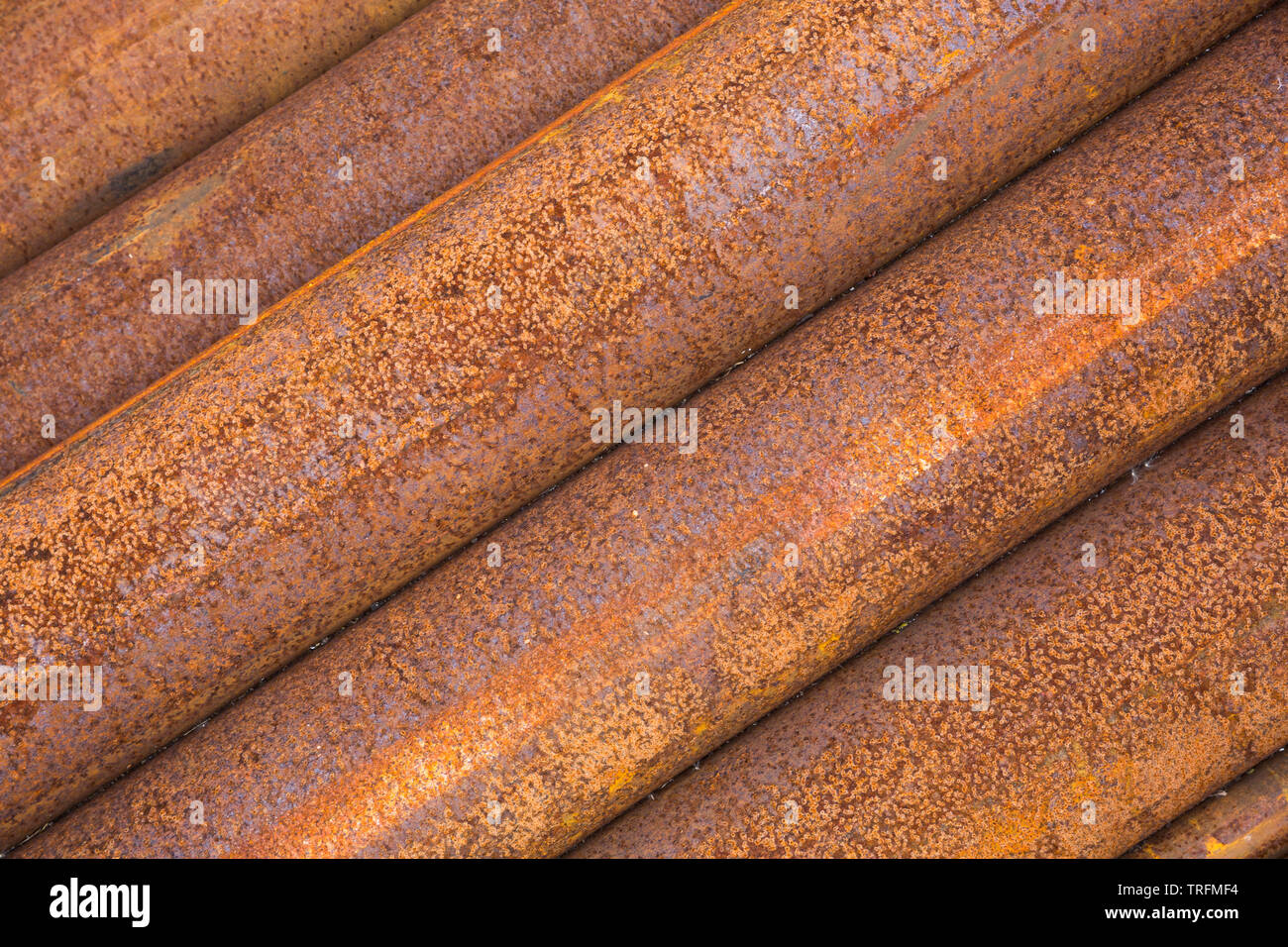 Angolato di close-up vista laterale di marrone e arancione lunghezze di ruggine tubolare in acciaio tubi impilati in una pila ordinata a Didcot Railway Centre, Oxfordshire, Regno Unito. Foto Stock