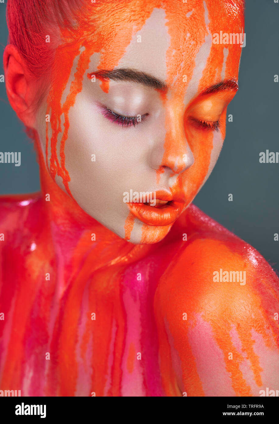 Modello di donna con il trucco e la perdita di colore arancione vernice al neon. Glitter vivid trucco. Alta Moda modello Foto Stock