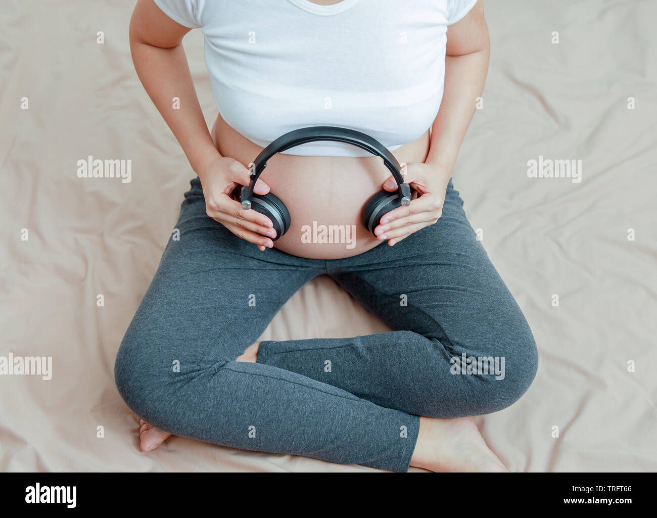 Donna incinta per ascoltare la musica con cuffie sulla pancia pancia Foto Stock