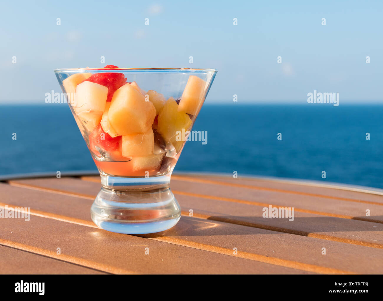 Miscelata fresca insalata di frutta su un tavolo di legno. Sfocato Sfondo oceano. Foto Stock