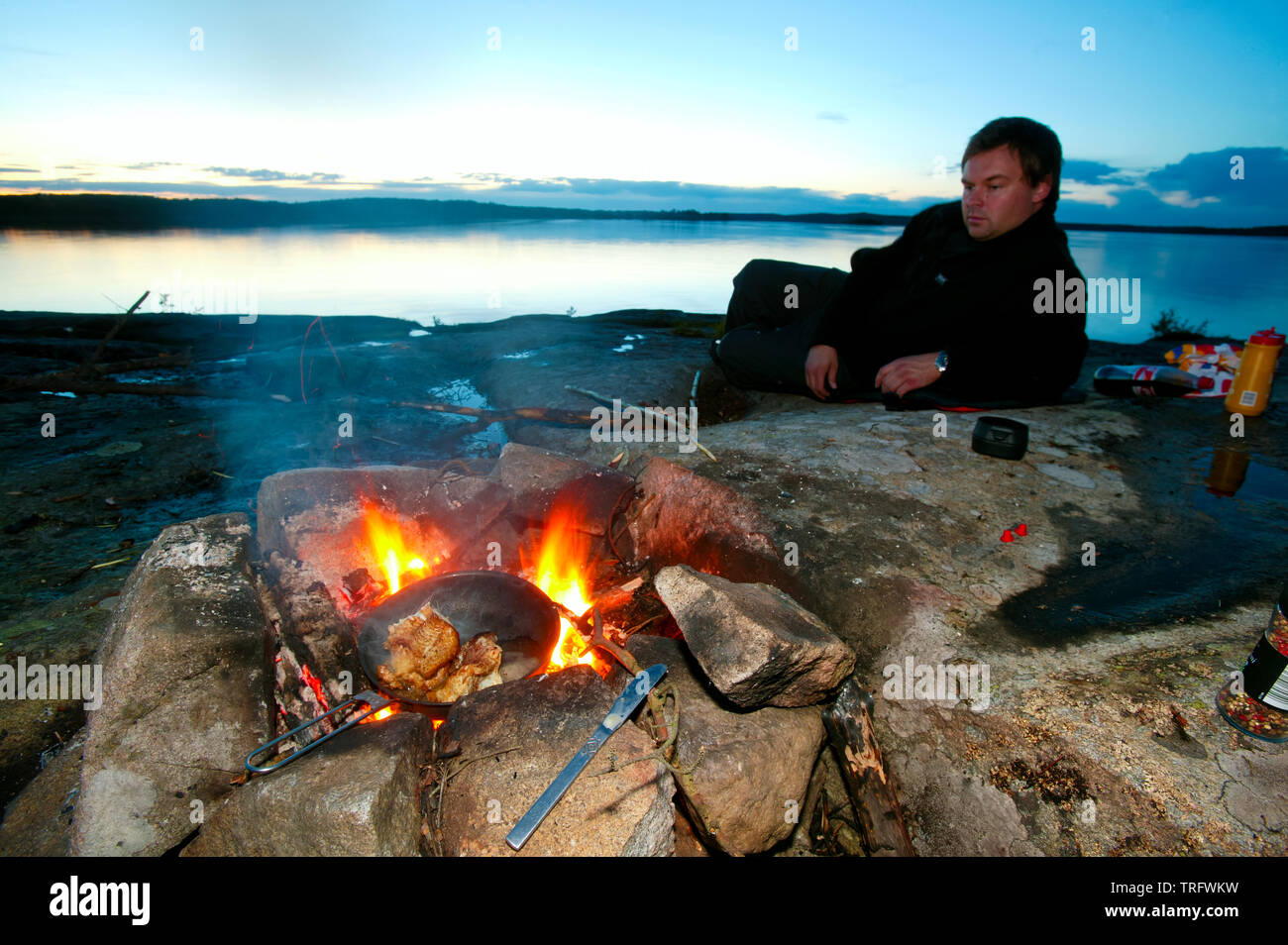 Jan Andre Ulriksen dai falò su una bella sera di settembre presso l'isola Brattholmen nel lago Vansjø, Østfold, Norvegia. Comune di persico fritto in padella. Vansjø è il lago più grande in Østfold. Il lago Vansjø e i suoi dintorni di laghi e fiumi sono una parte dell'acqua sistema chiamato Morsavassdraget. Settembre, 2006. Foto Stock