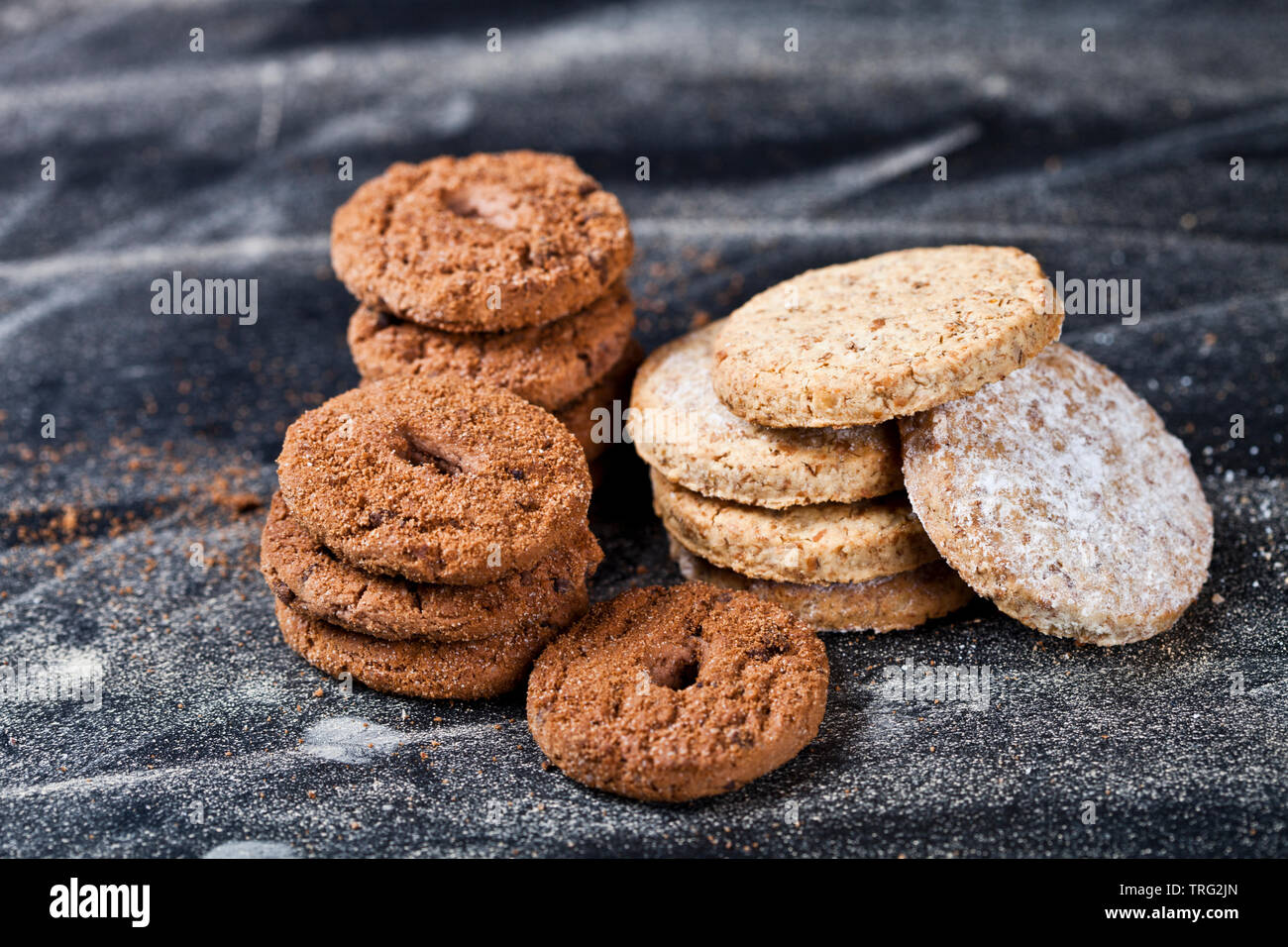 Chocolate Chip e oat biscotti freschi con lo zucchero in polvere di pile su sfondo nero. Foto Stock