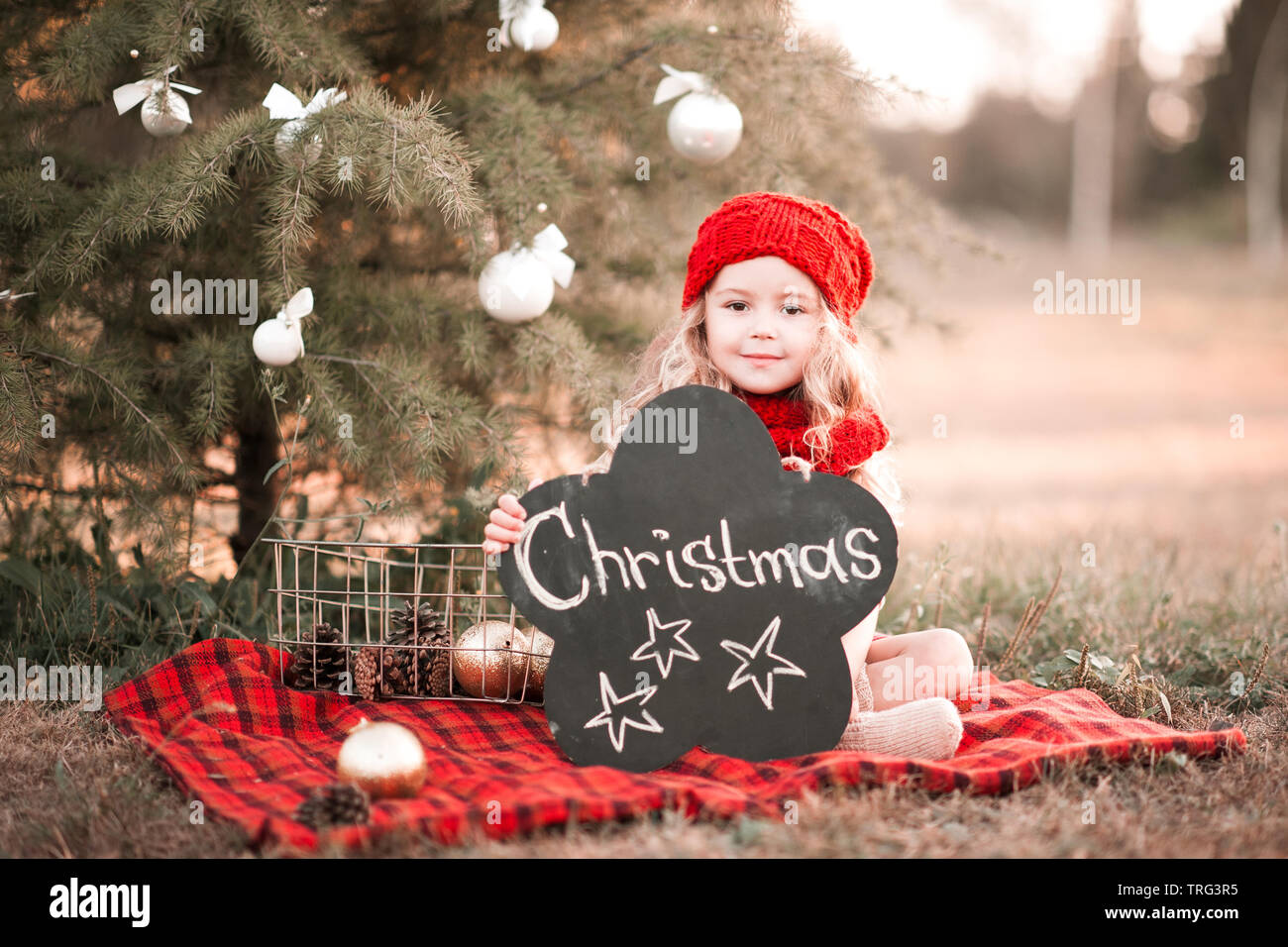 Carino kid girl 3-4 anno vecchio con decorazioni di Natale all'esterno. Guardando alla fotocamera. Stagione di vacanze. Infanzia. Foto Stock