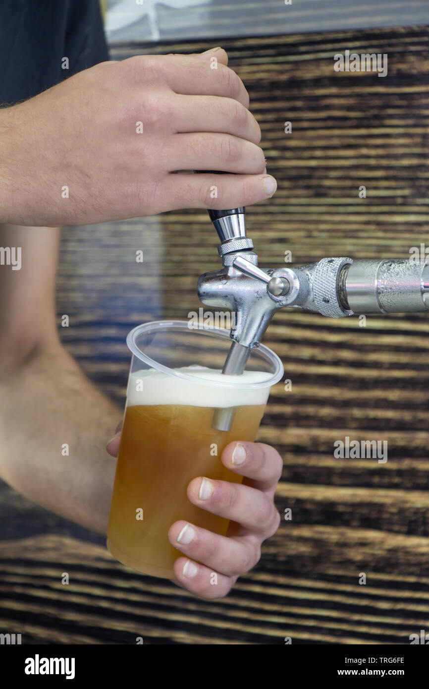 Barman il riempimento di vetro di plastica con birra chiara Foto Stock