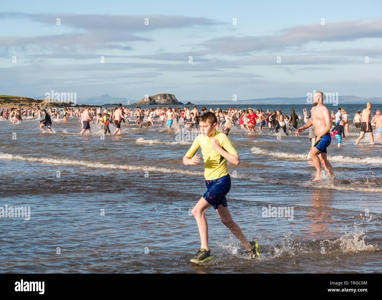 Loony Dook , il giorno di Capodanno: persone brave l'acqua fredda, West Bay, Firth of Forth, North Berwick, East Lothian, Scozia, Regno Unito. Persone corrono in mare Foto Stock