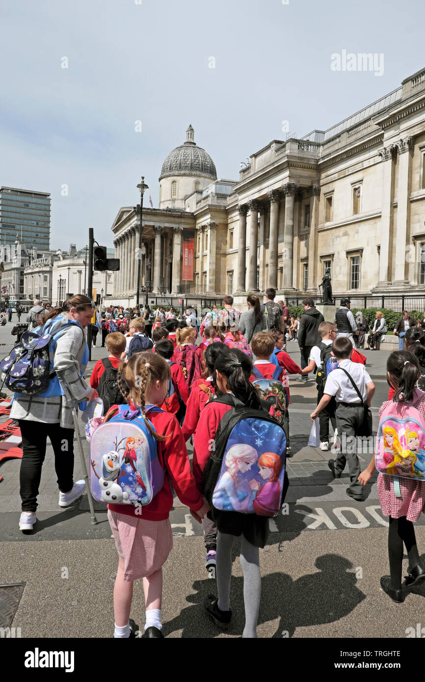 Gli alunni della scuola primaria di ragazze e ragazzi con Disney zaini a piedi lungo la strada per visitare la Galleria Nazionale Centrale di Londra Inghilterra KATHY DEWITT Foto Stock