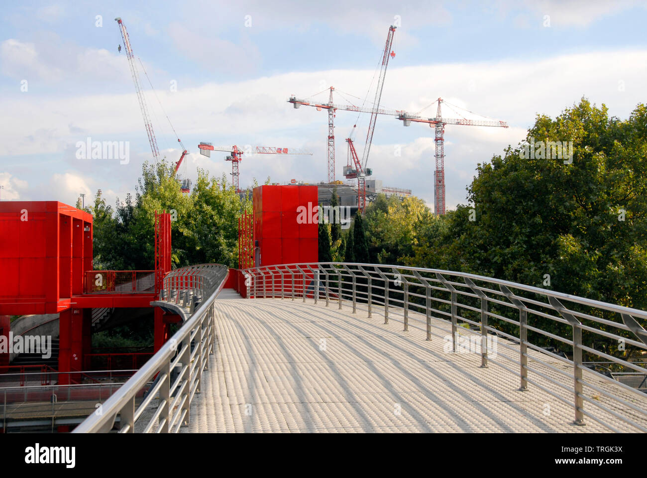 Diverse gru per edilizia in distanza con ponte curvo su canal e strutture di rosso in primo piano, Parigi, Francia Foto Stock