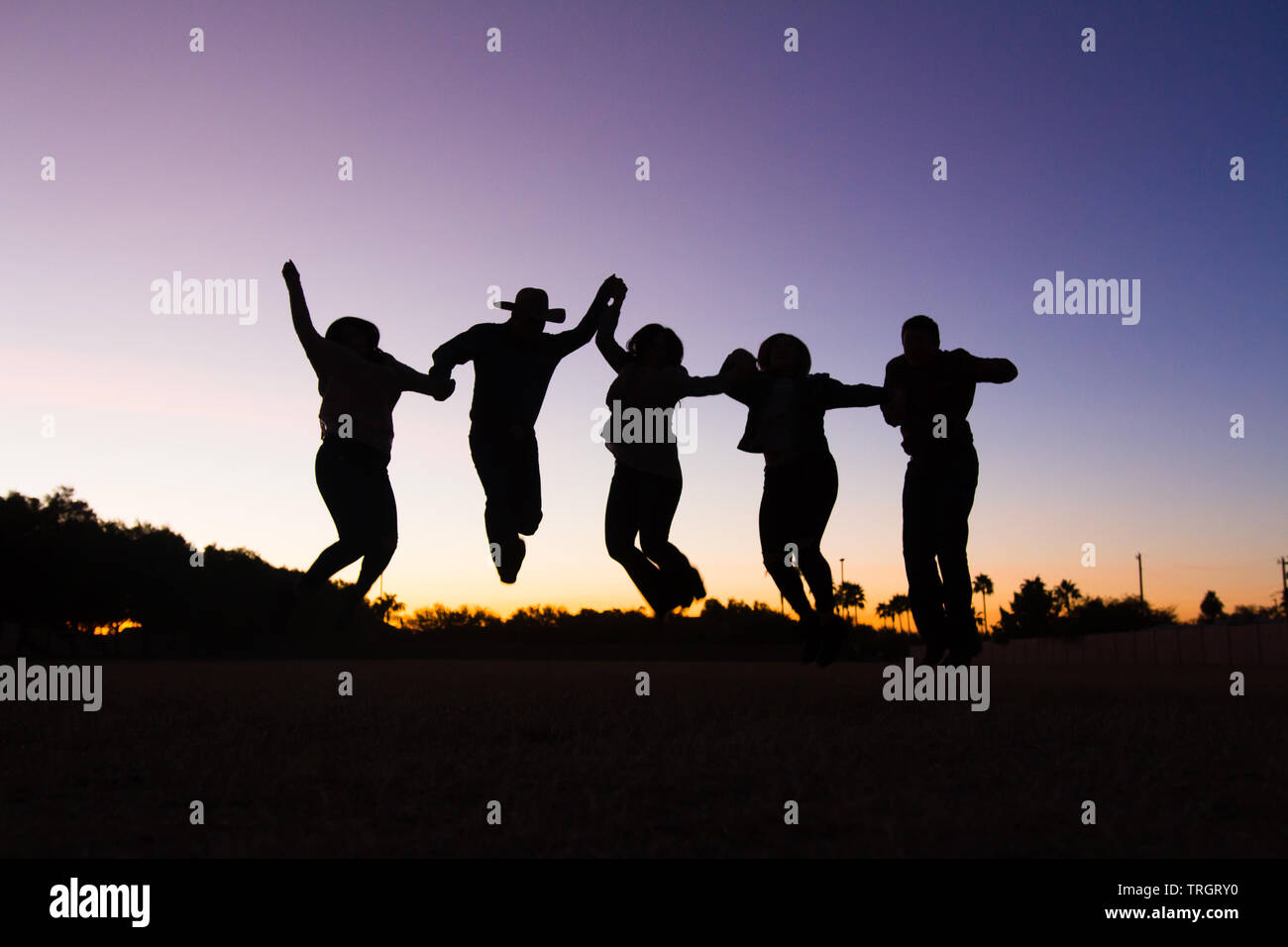 Famiglia di campagna nel tramonto danzare e saltare Foto Stock