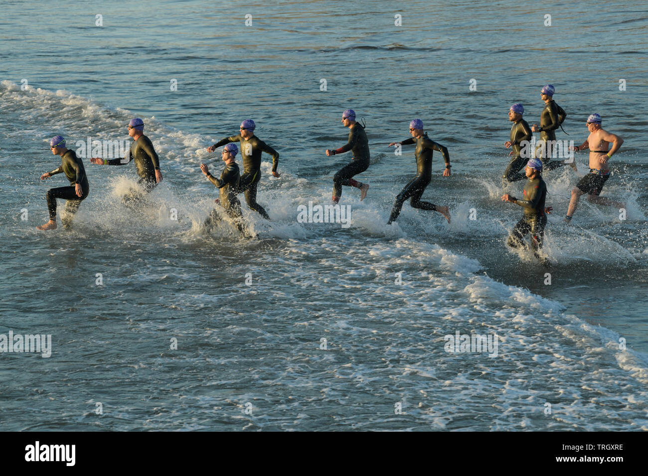 Triatleti in esecuzione attraverso il surf, avviare, nuoto gamba, triathlon, 2019, Ironman 70,3, Durban, KwaZulu-Natal, Sud Africa, persone, splash, muta Foto Stock