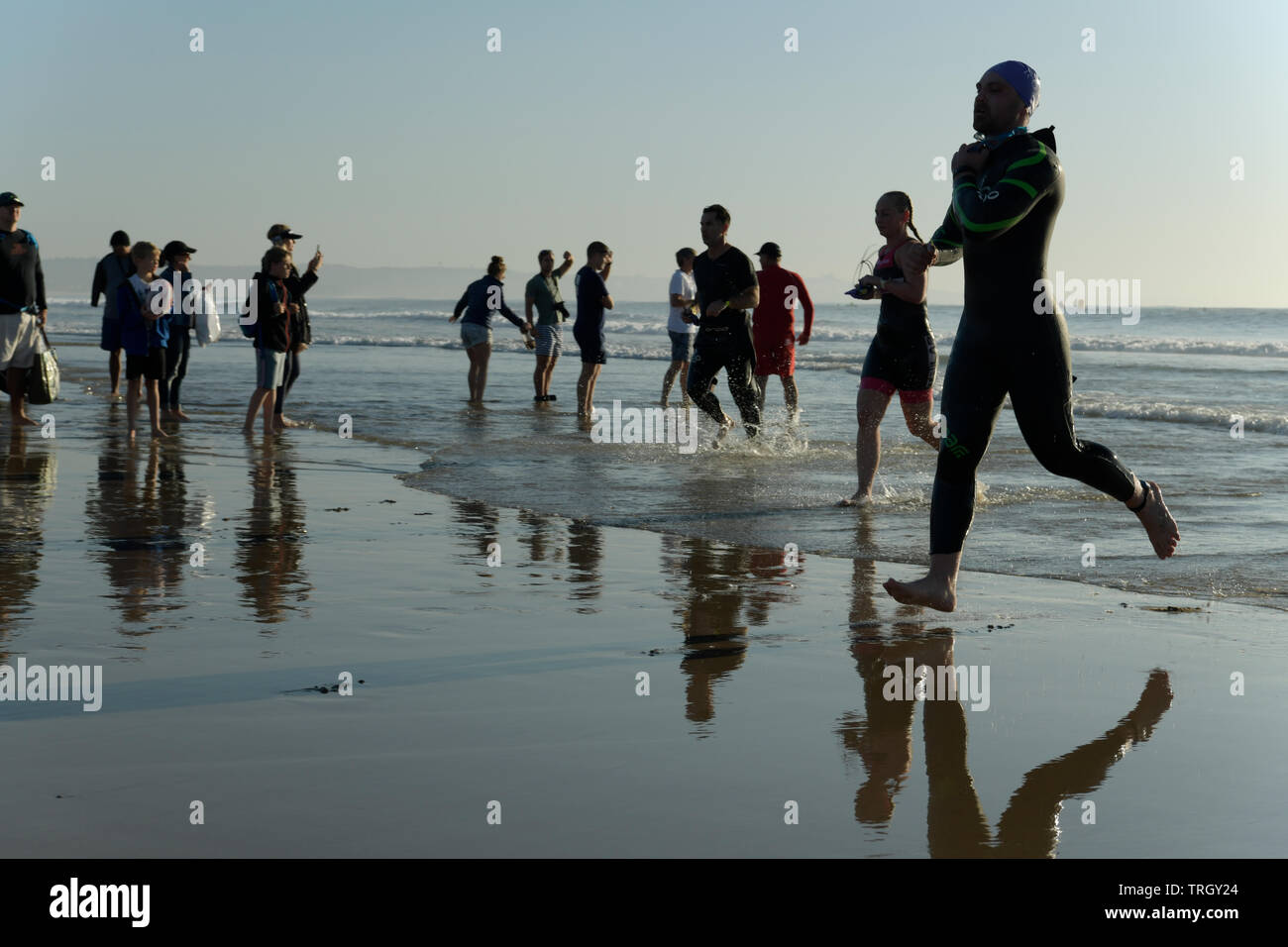Durban, Sud Africa, gli atleti in esecuzione, concorrenti uscire acqua alla fine della gamba di nuoto, 2019, Ironman 70,3, silhouette, spettatori, sport, persone Foto Stock