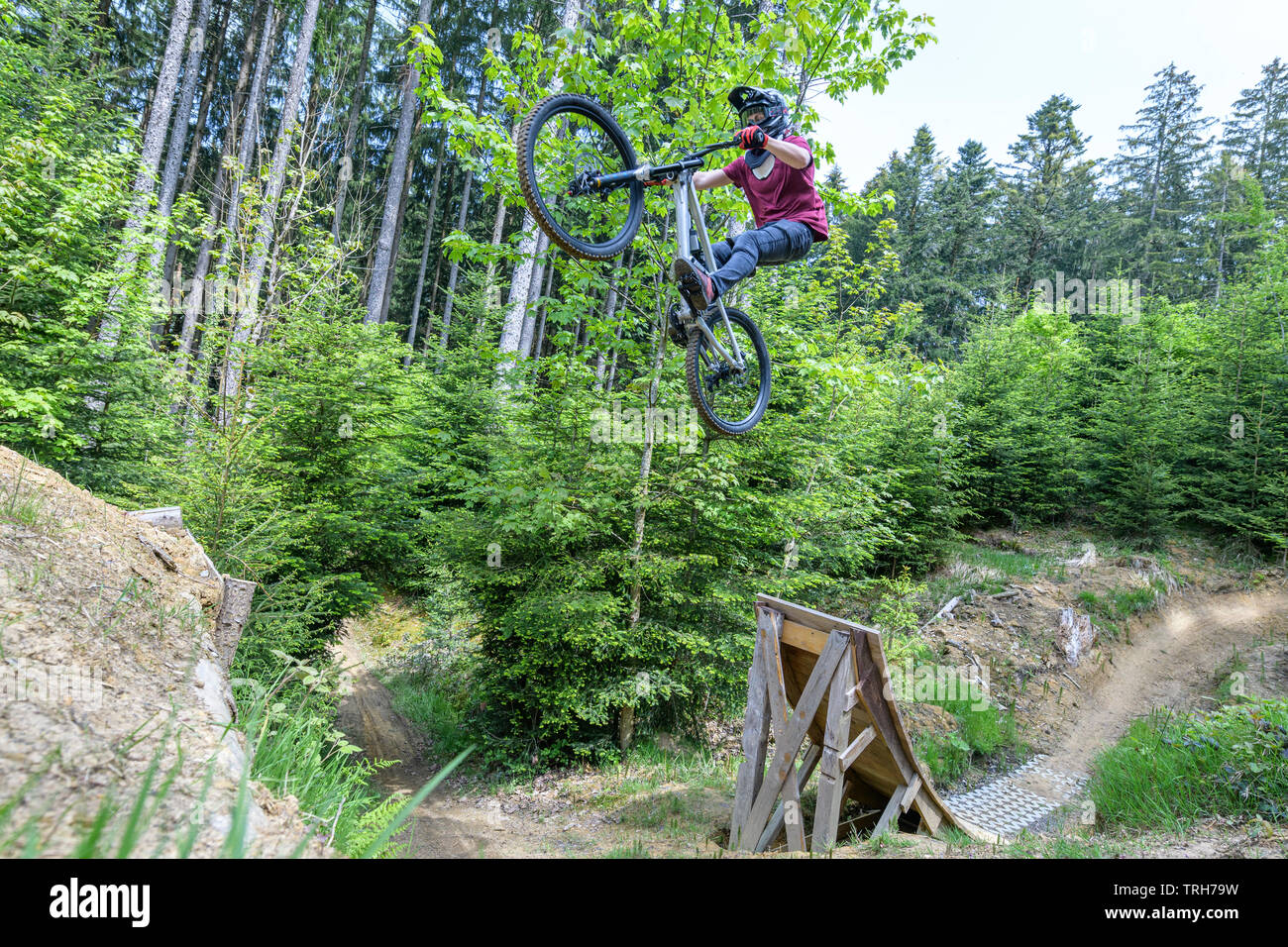 Sessione di salto di giovani professionisti della mountain bike in un bike park in foresta Foto Stock