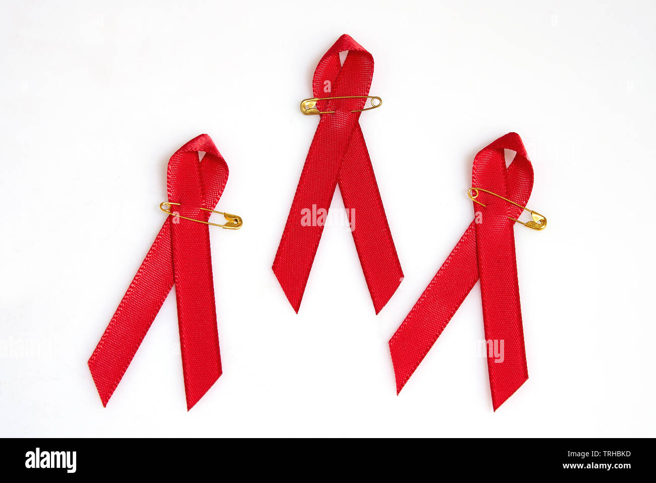 Nastri di rosso con perni d'oro per il concetto di Aids isolato su bianco Foto Stock