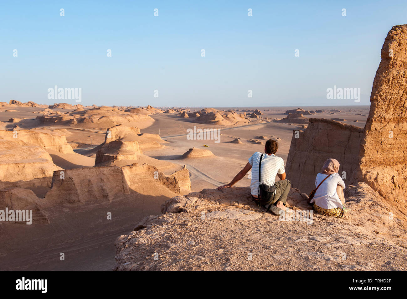 I turisti guardano il sole tramontare sugli yardangs nel deserto LUT a Shahad, Iran. Conosciuta come le malghe in Iran, gli yardangs sono formazioni geologiche. Foto Stock