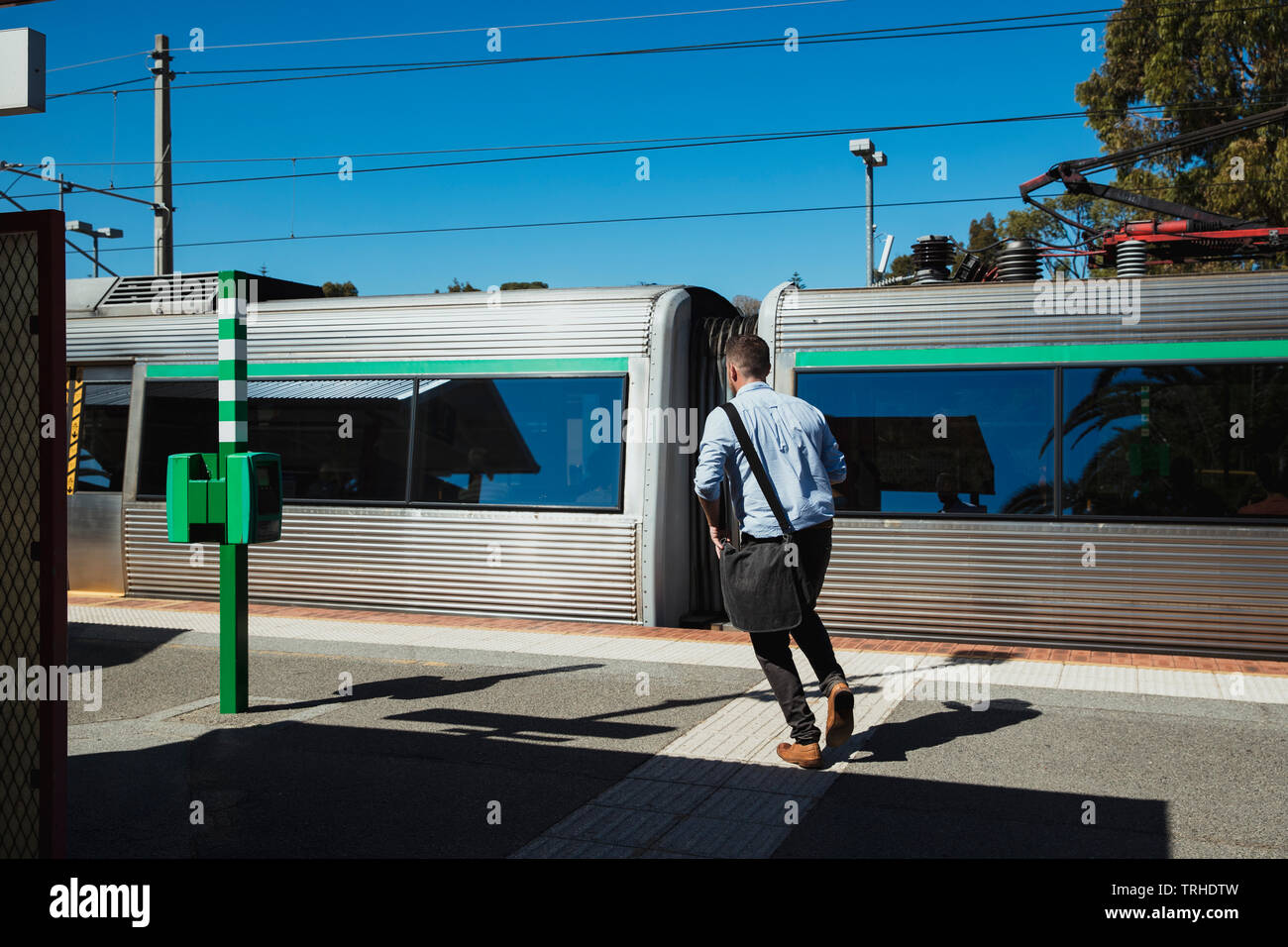 Una vista posteriore colpo di una metà degli adulti imprenditore caucasico correre giù per una stazione ferroviaria piattaforma, egli sta cercando di prendere il treno. Foto Stock