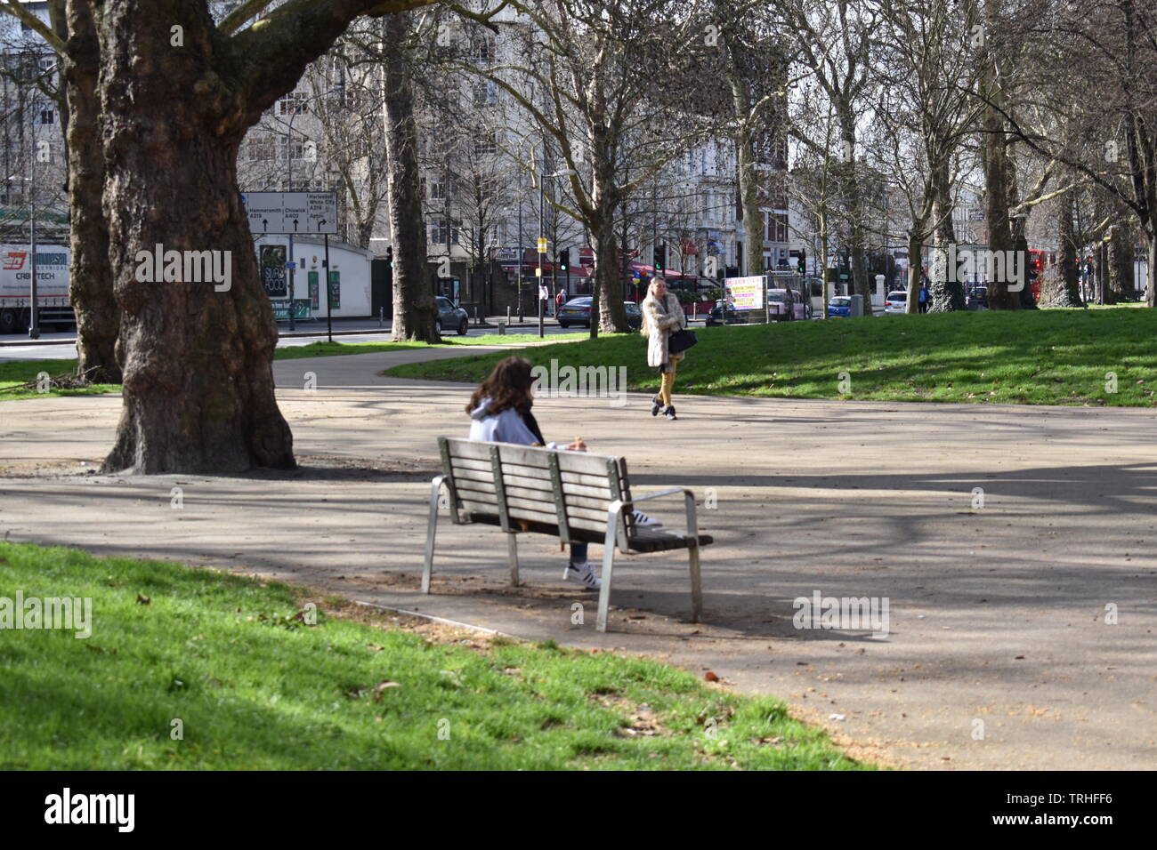 Giovane donna seduta su una panchina nel parco Foto Stock