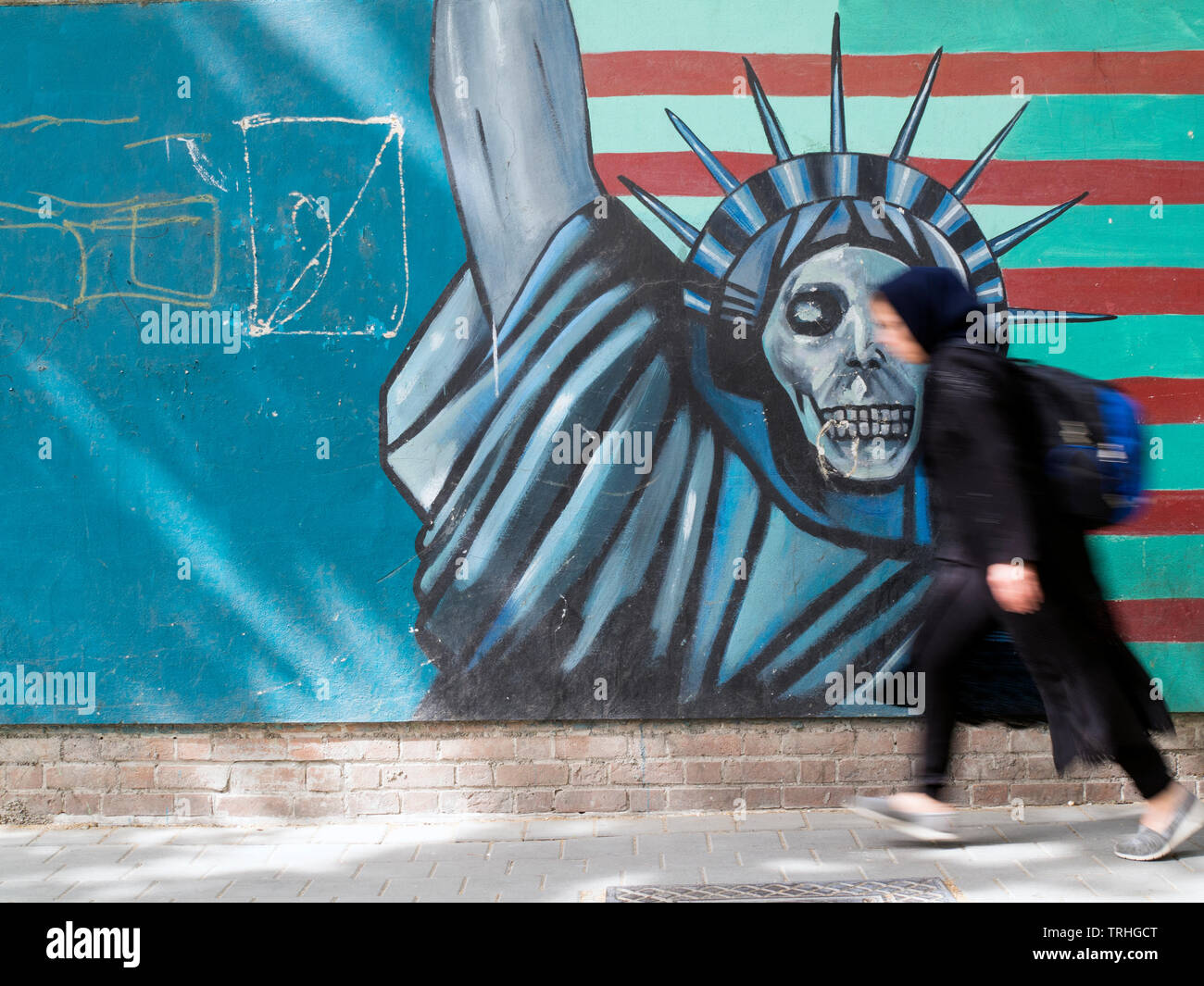 Un pedone passa accanto a un murale raffigurante la Statua della libertà come morte dipinta sul muro dell'ex ambasciata americana a Teheran, Iran. Foto Stock