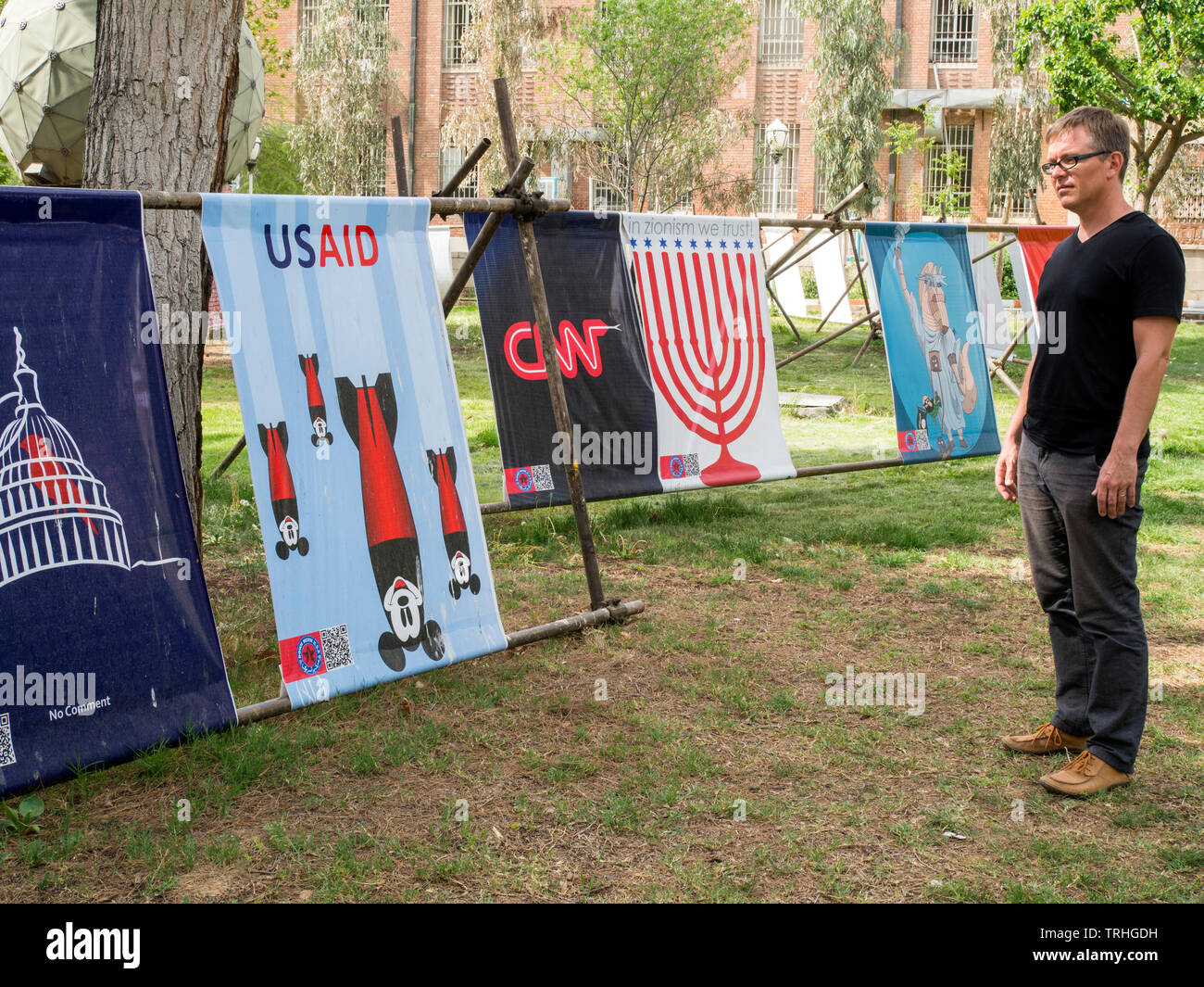 Un turista europeo guarda i manifesti di propaganda al Museum Garden of Anti Ararrogance, ospitato nell'ex Ambasciata americana a Teheran, Iran. Foto Stock