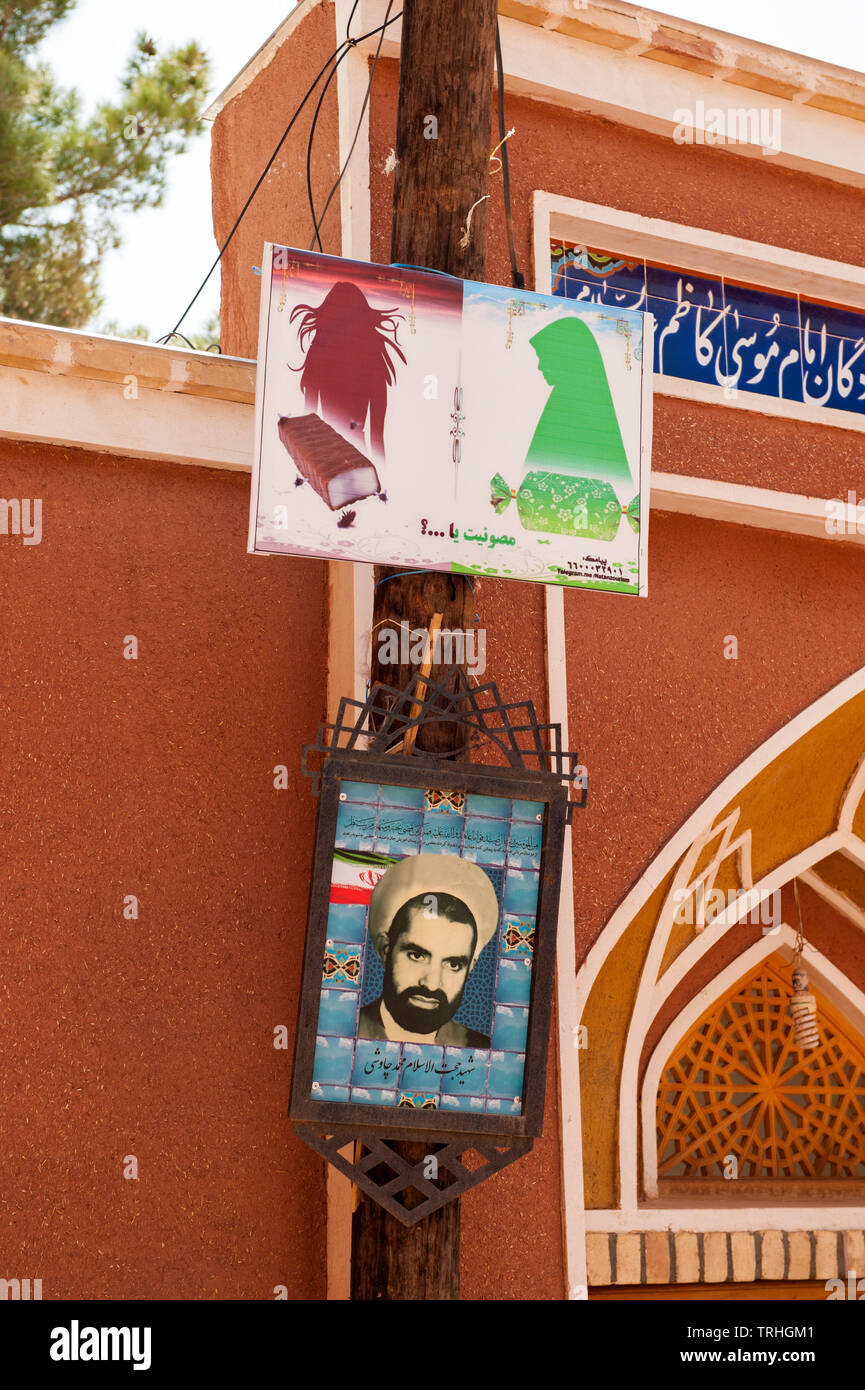 Una foto del martire che morì durante la guerra Iran-Iraq e un segno per incoraggiare le donne ad indossare il hijab o un velo in Abyaneh, Iran. Foto Stock