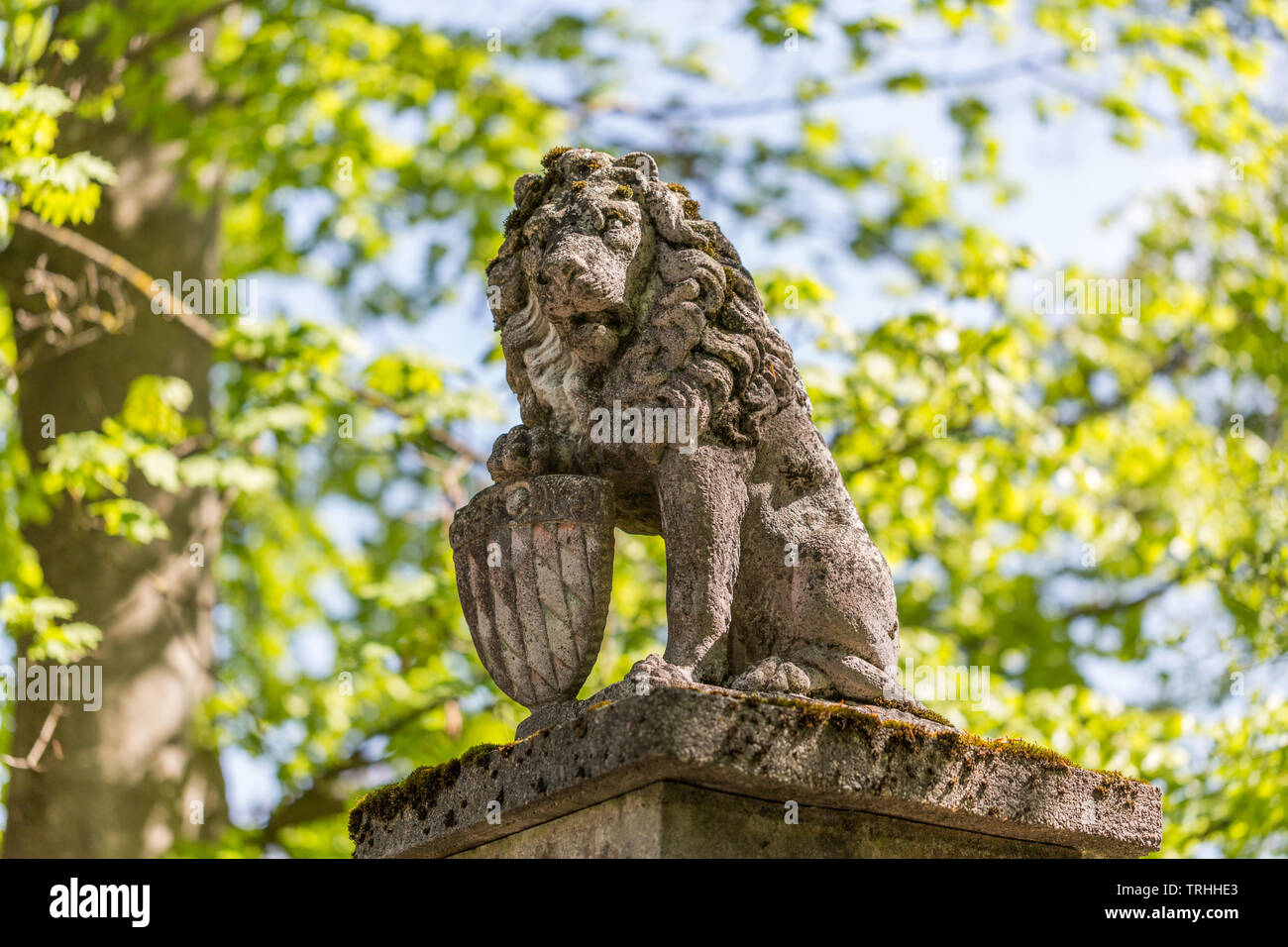 Statua di Pietra del leone bavarese, tenendo una protezione con il modello di diamante della bandiera bavarese. La statua custodisce l'entrata di una station wagon in Baviera. Foto Stock