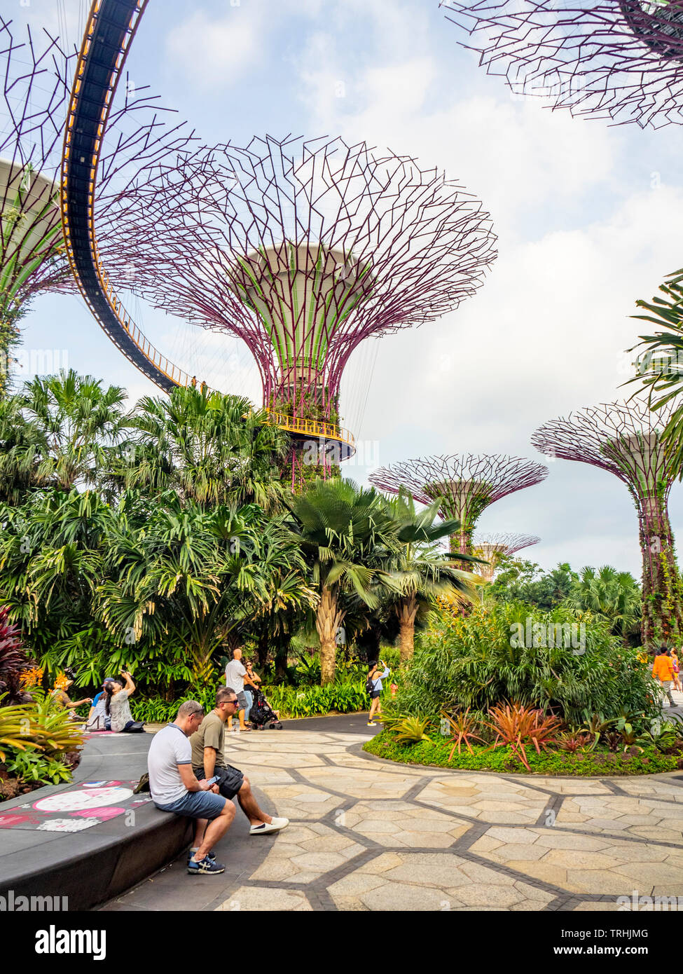 I turisti seduti al basamento in cemento di un Supertree presso i giardini dalla Baia di Singapore. Foto Stock
