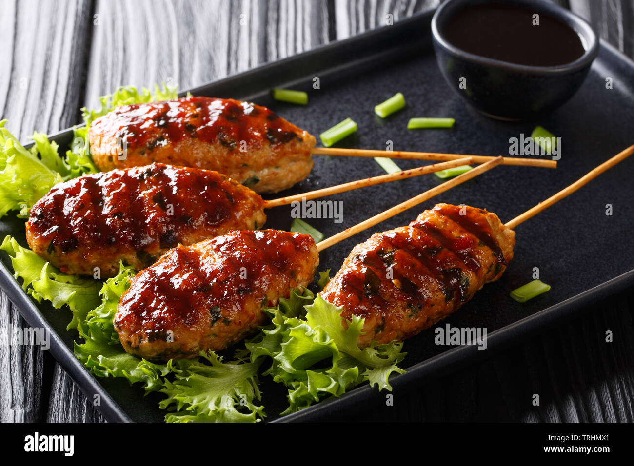 Tsukune giapponese polpette di pollo, infilzato e tipicamente alla griglia su carbone close-up su una piastra sul tavolo. Posizione orizzontale Foto Stock