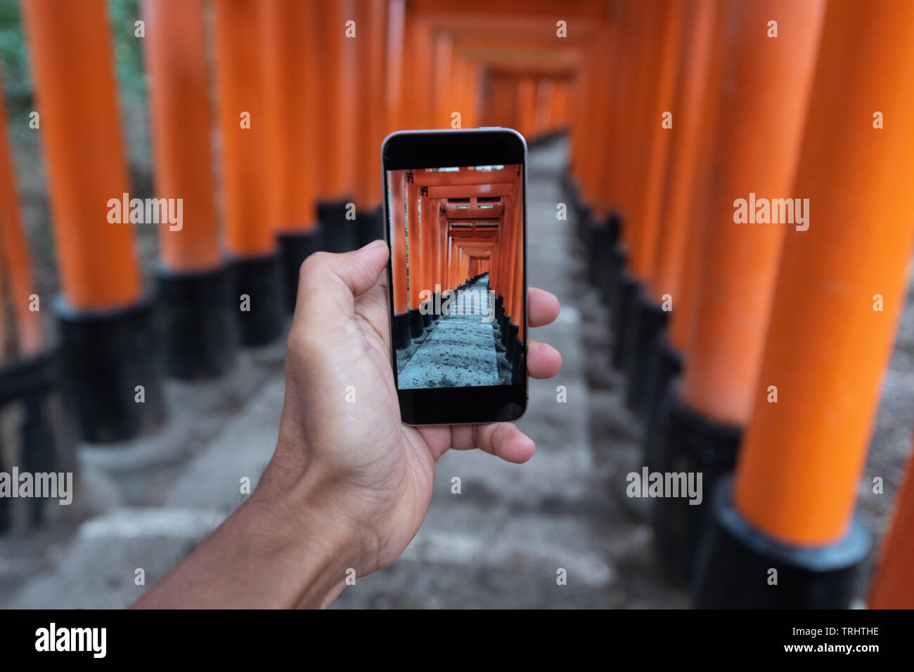 Torii gates nel Fumishi Inari santuario a Kyoto, Giappone visto attraverso uno smartphone Foto Stock