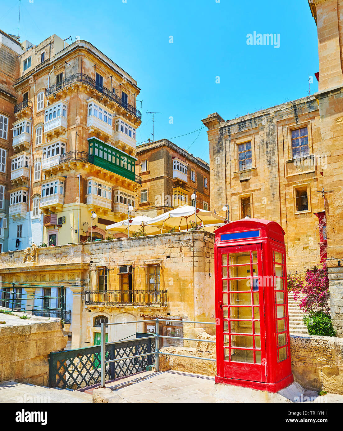 La scena urbana nella città vecchia con una vista sulla vita medievale case e vintage telefono rosso casella sul primo piano, Valletta, Malta. Foto Stock