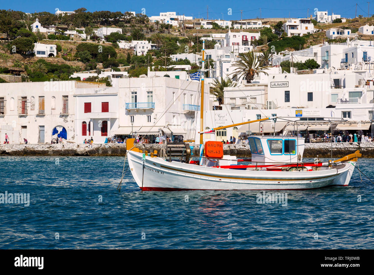 La pesca in barca in porto con una collina della città di Mykonos. Giornata di sole a Mykonos, Grecia, a fine giornata nel mese di maggio. Foto Stock
