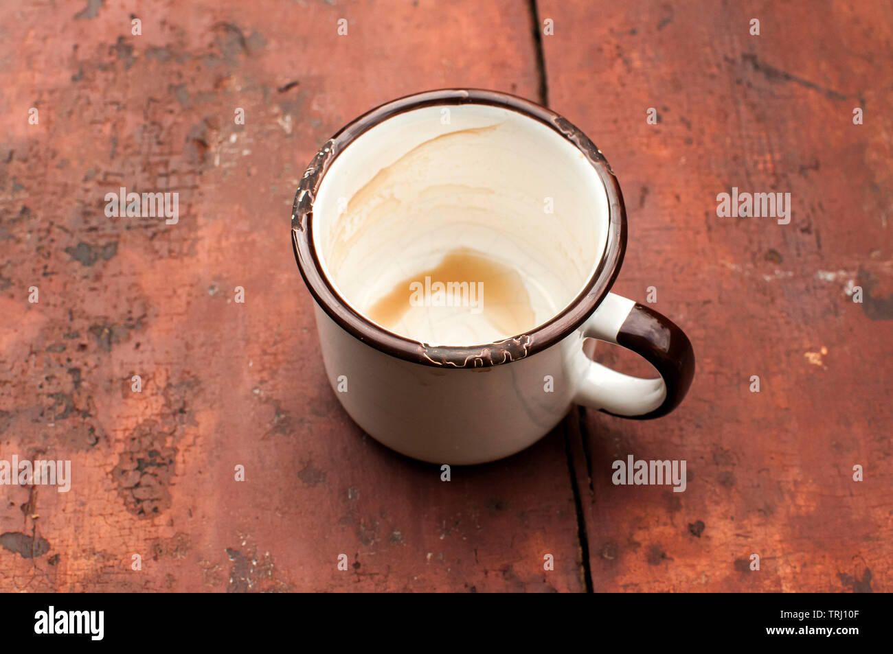 Smalto metallico mug con resti di bere caffè sulla vecchia tabella di dipinto di grunge superficie di schede Foto Stock