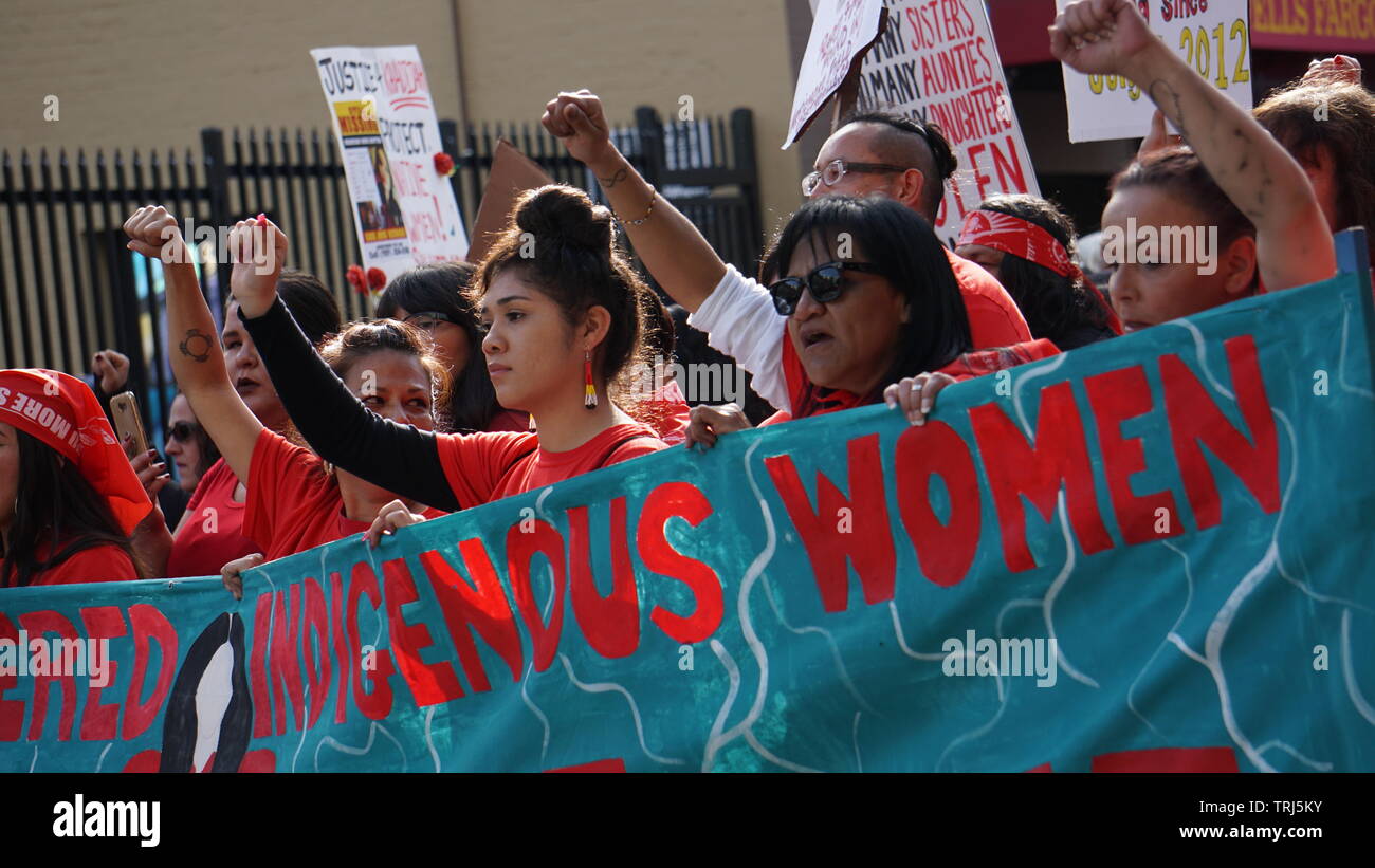 Gli indigeni o nativi americani le donne in marcia con un banner con i pugni in aria. 2019 Donna Marzo, Market Street, San Francisco, California, Stati Uniti d'America. Foto Stock