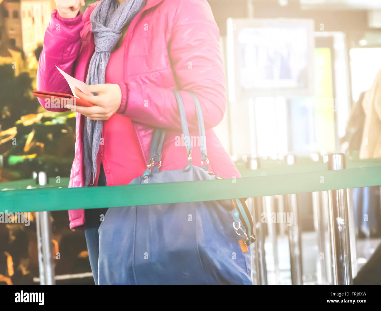 Irriconoscibile donna con una camicia rosa appena trattiene il passaporto in mano per i controlli di sicurezza prima di salire a bordo di un aereo Foto Stock