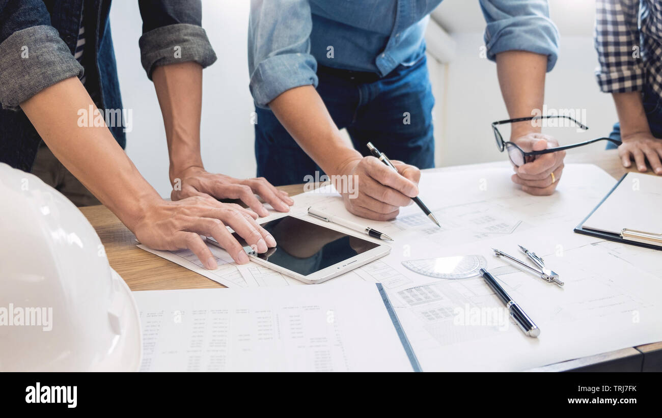 I progettisti in sede di discussione di lavoro architetto Blueprint su un nuovo progetto Progettazione disegnare il lavoro di squadra sulla scrivania in legno Foto Stock