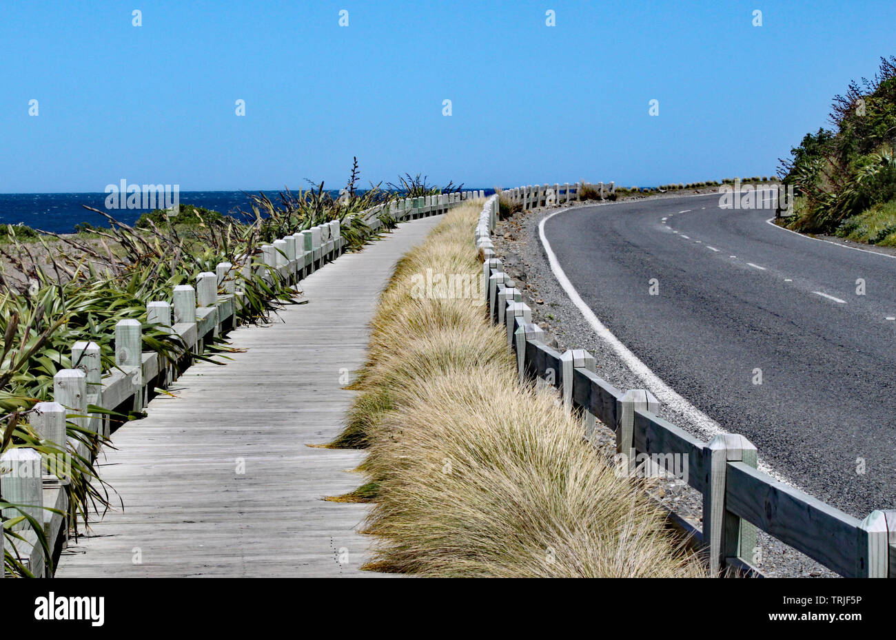 Quieta e tranquilla strada costiera e la passerella di legno vicino a Wellington, Nuova Zelanda. Foto Stock