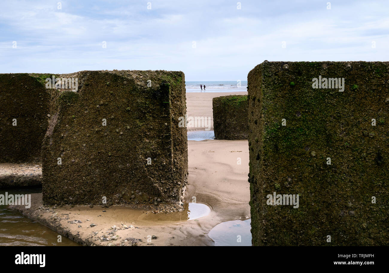 Massi di calcestruzzo utilizzato come le difese del mare durante la guerra mondiale 2 presentata in sabbia sulla spiaggia con la bassa marea sul mattino luminoso, Fraisthorpe, nello Yorkshire, Regno Unito. Foto Stock