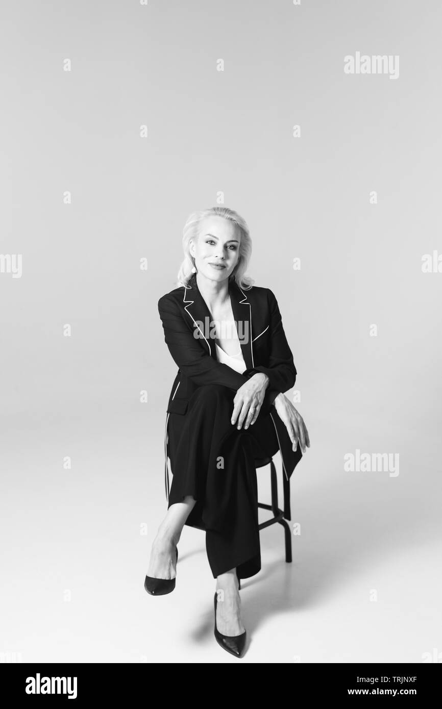 Ritratto in studio di bella donna bionda in un abito nero contro bianco sfondo semplice Foto Stock