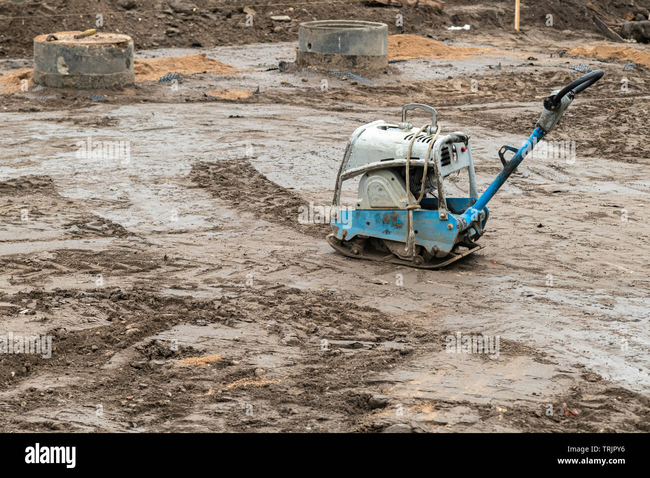 Compattatore a piastra sul terreno al sito in costruzione. Martello vibrante power tool, jumping jack macchina comprimendo la massa Foto Stock