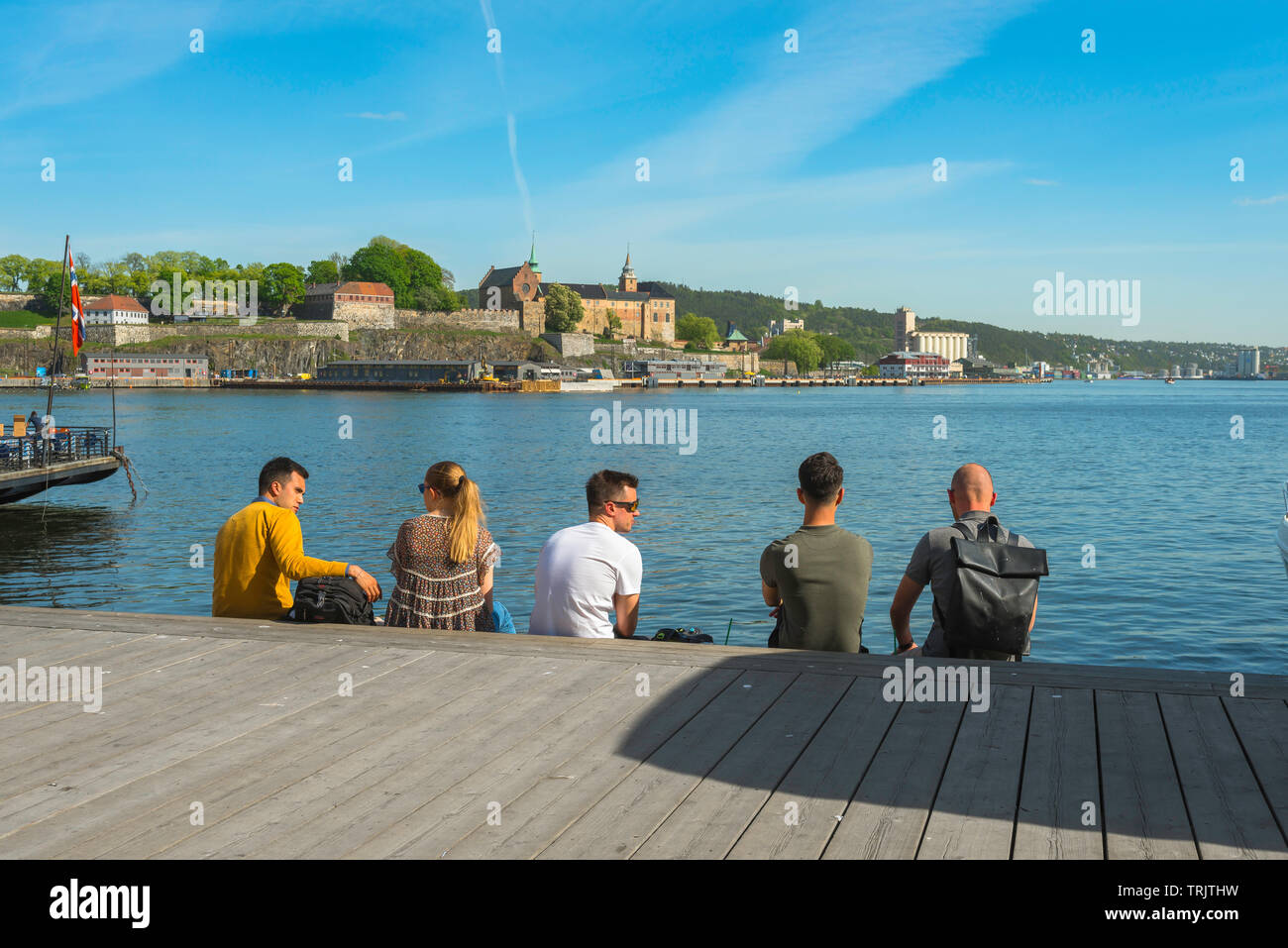 Gli amici di parlare, visualizzare un pomeriggio estivo di amici Norvegesi rilassante lungo la Aker Brygge waterfront nel porto di Oslo, Norvegia. Foto Stock