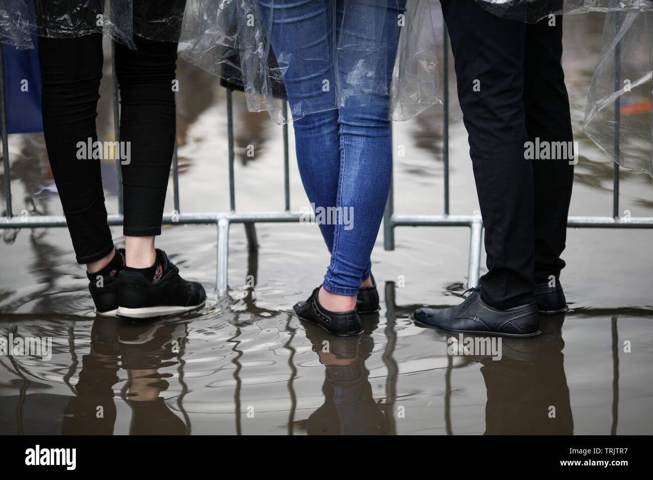 Dettagli con i piedi dei giovani in piedi in acqua a un incontro pubblico (festival di musica) Foto Stock
