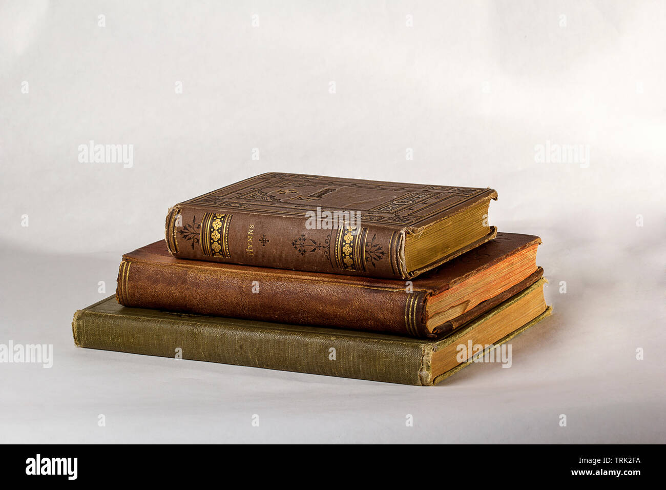 Pila di tre libri antichi su uno sfondo bianco. Foto Stock