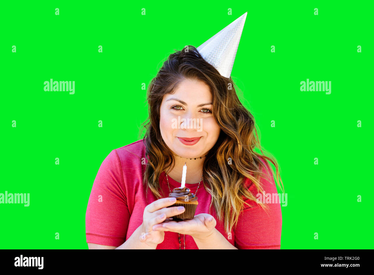 Donna sorridente detiene un compleanno cupcake su schermo verde Foto Stock