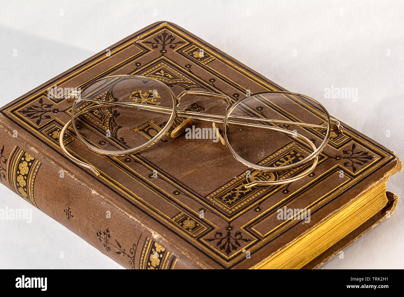 Un paio di occhiali antichi seduti su un vintage hymnal su uno sfondo bianco. Foto Stock