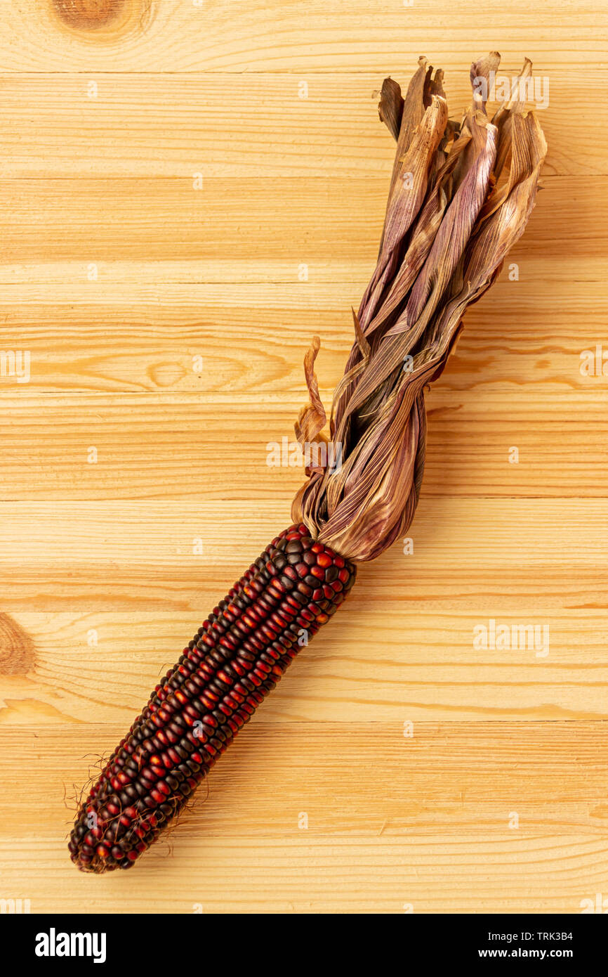 Un colorato di mais vitreo giace su un golden pine tavolo. Foto Stock