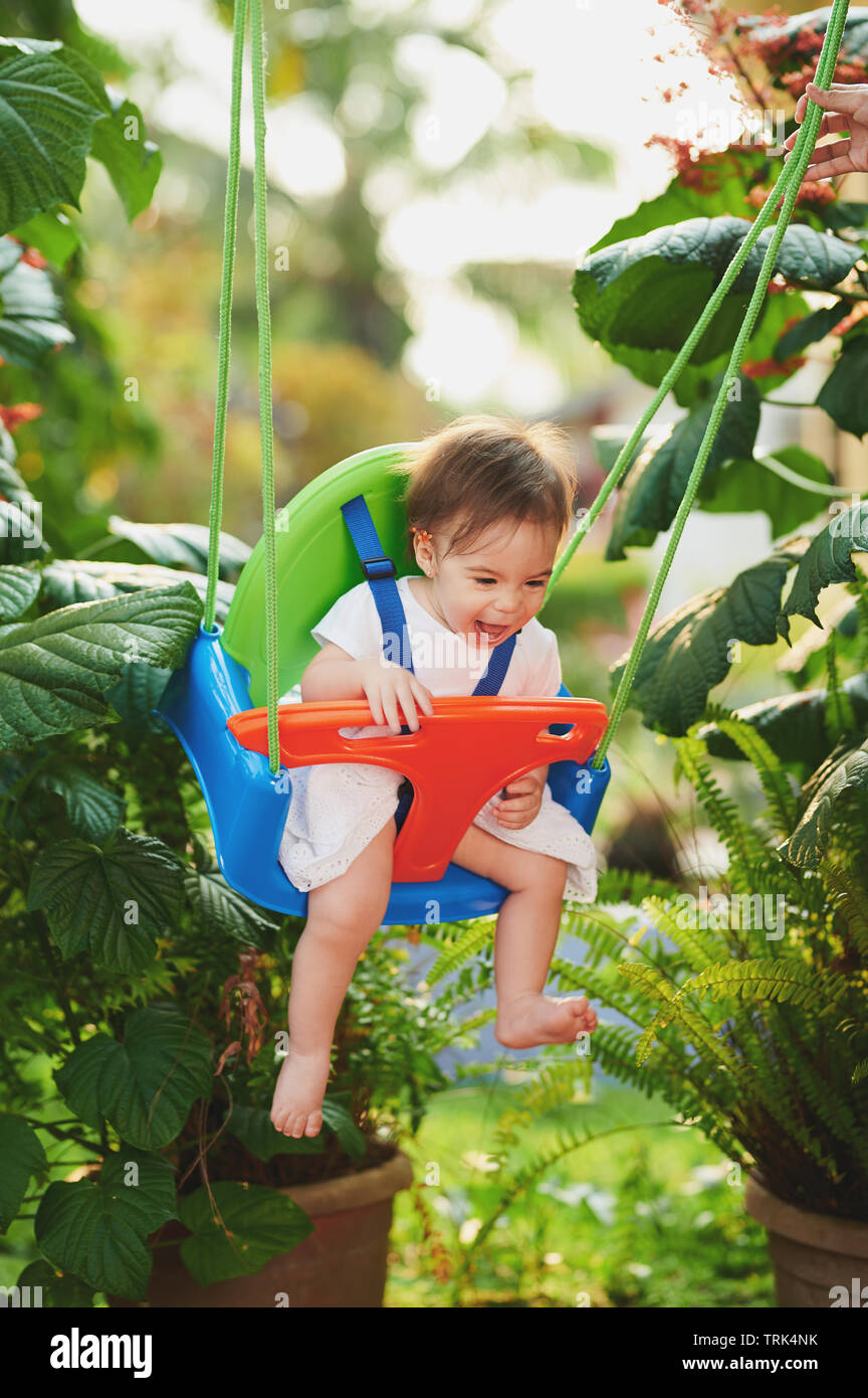 Sorridenti Baby girl su swing sul giardino sfocata sullo sfondo Foto Stock