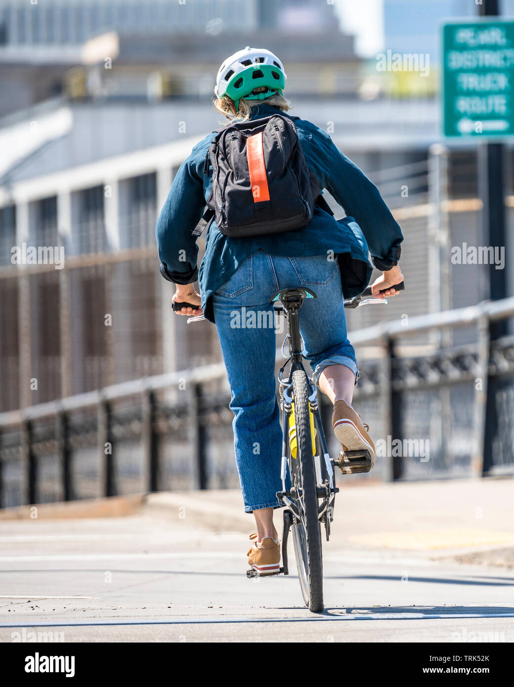 La donna corse in bicicletta su una pista ciclabile. L'uso di una bicicletta come mezzi di trasporto principali per molti appassionati è cresciuto da un hobby in una necessità vitale per m Foto Stock