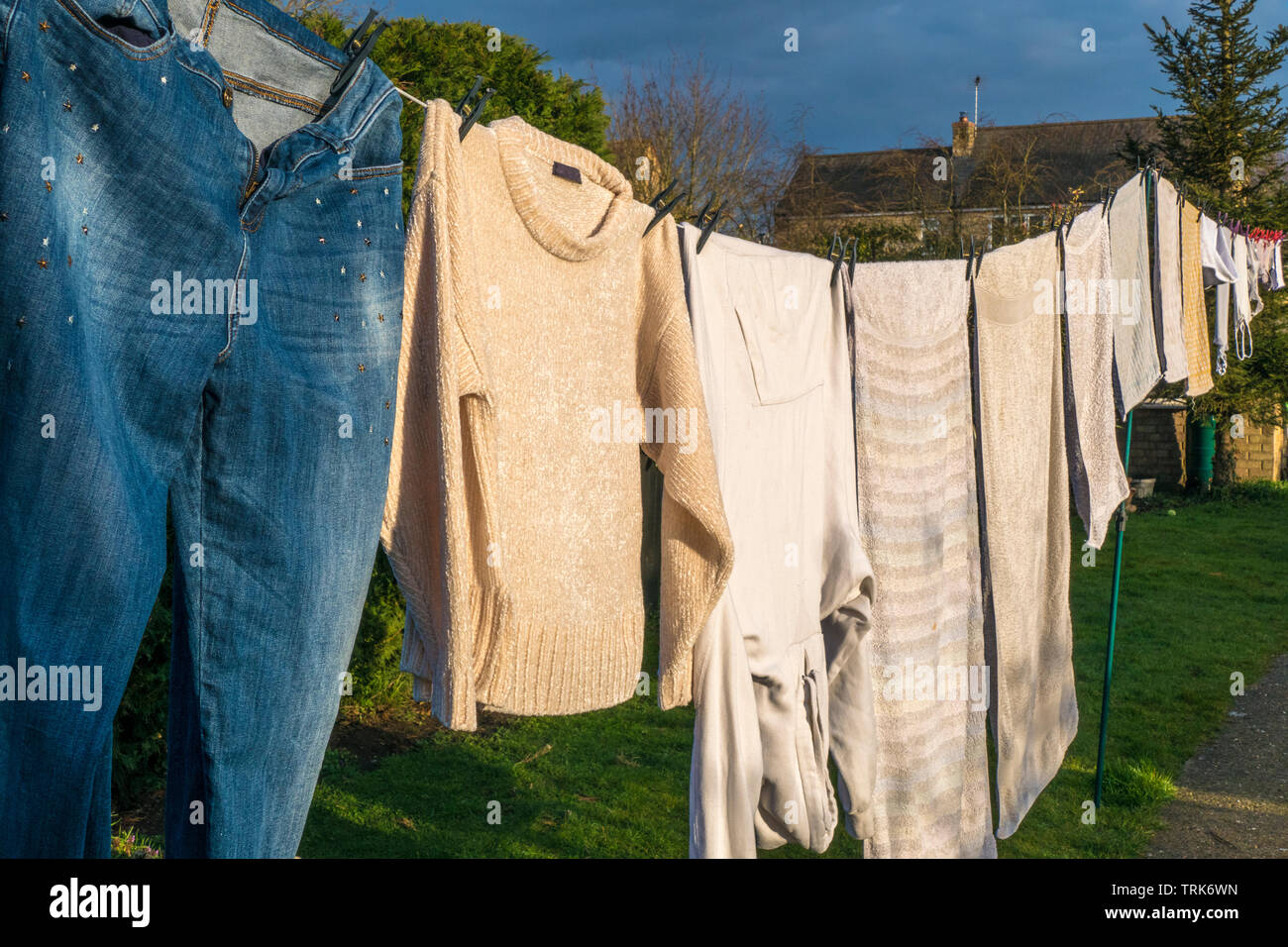Vista laterale del bucato domestico di vestiti bagnati e asciugamani, ancorato e appesa ad asciugare su una linea di lavaggio nel caldo sole del pomeriggio. Inghilterra, Regno Unito. Foto Stock