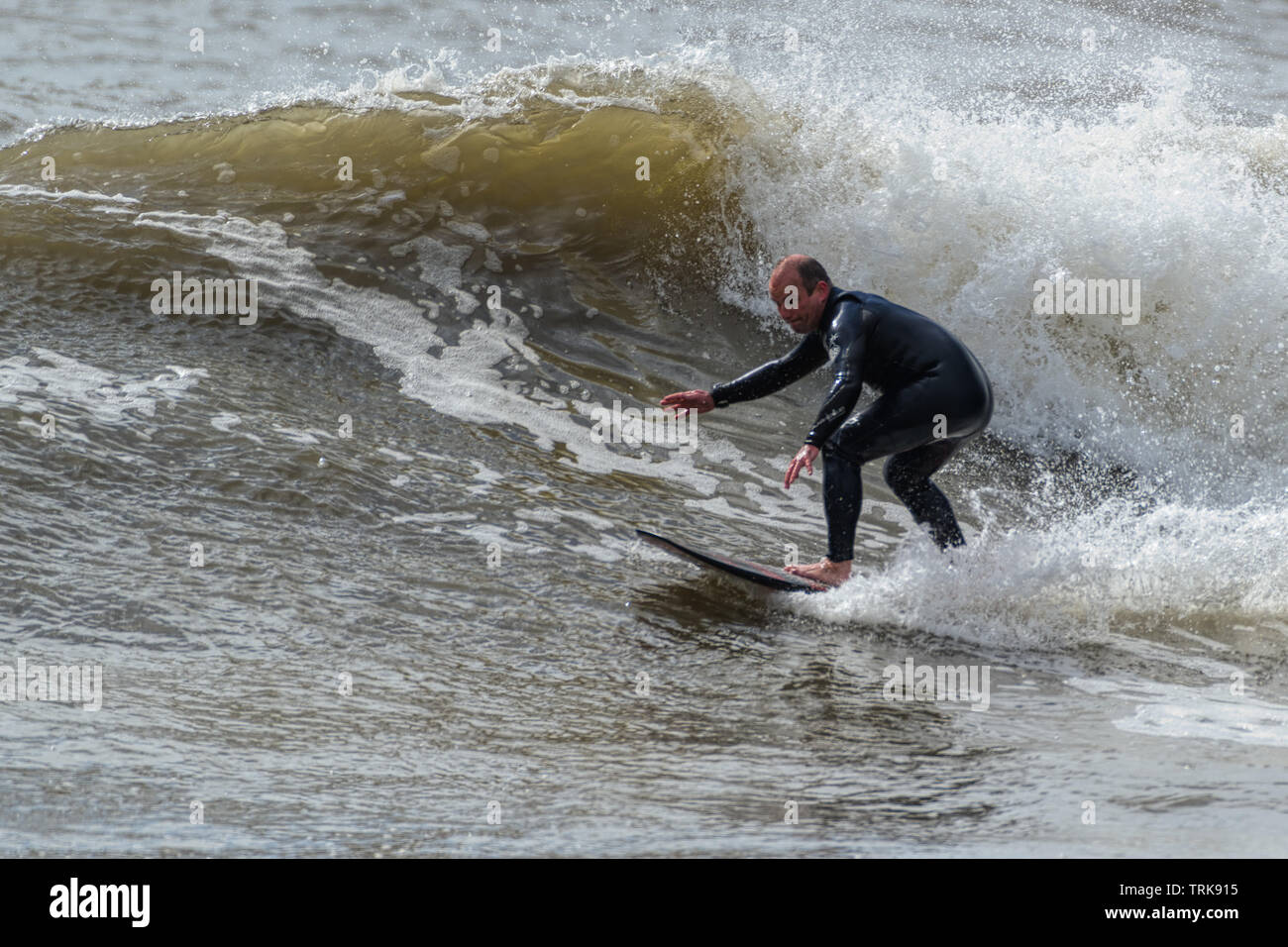 Persone di mezza età surfer mostra il suo stile. Resto Bay Porthcawl, Regno Unito. Foto Stock