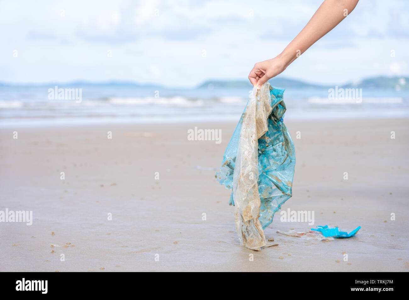 Donna di raccolta a mano fino utilizzato il sacchetto in plastica sulla spiaggia di sabbia, pulizia spiaggia balneare. Inquinamento ambientale, il problema ecologico e di inquinamento marino con Foto Stock