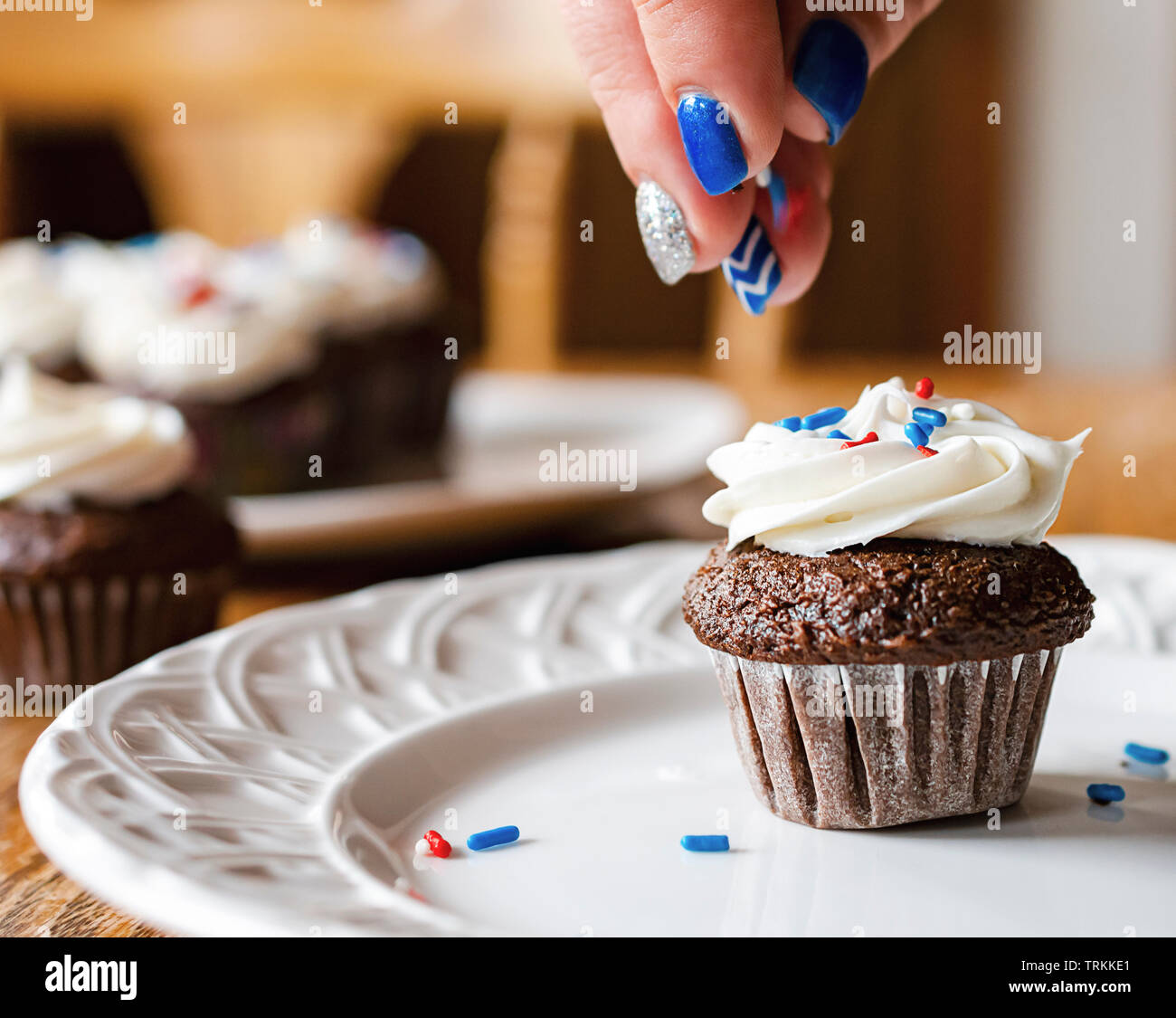 Mini cupcake è irrorato con rosso, bianco e blu spruzza. Tortini sfocata in background. Foto Stock